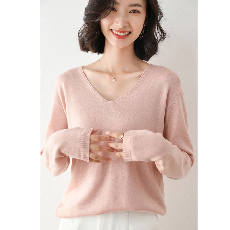 Frau trägt rosa V-Ausschnitt Pullover, lächelt, modisch, elegant, Damenmode, Strickware.