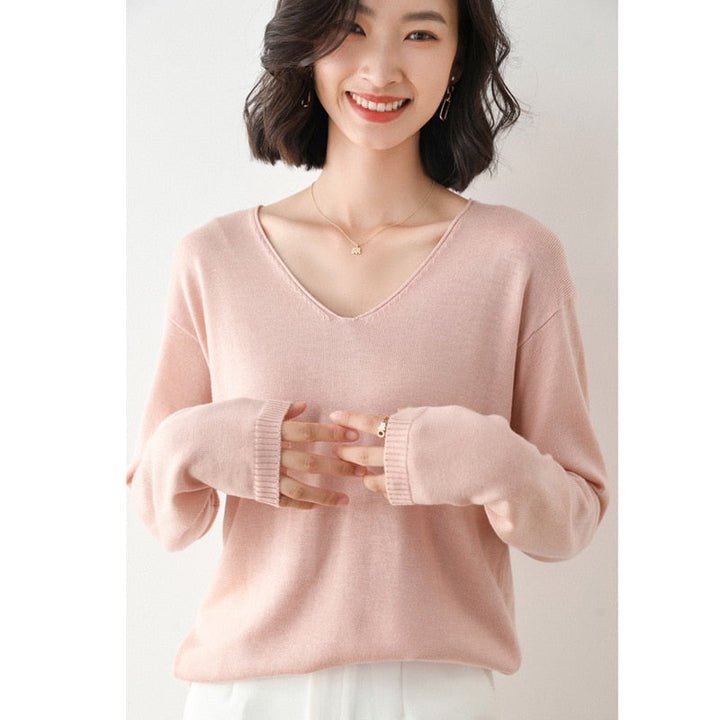 Frau trägt rosa V-Ausschnitt Pullover, lächelt, modisch, elegant, Damenmode, Strickware.