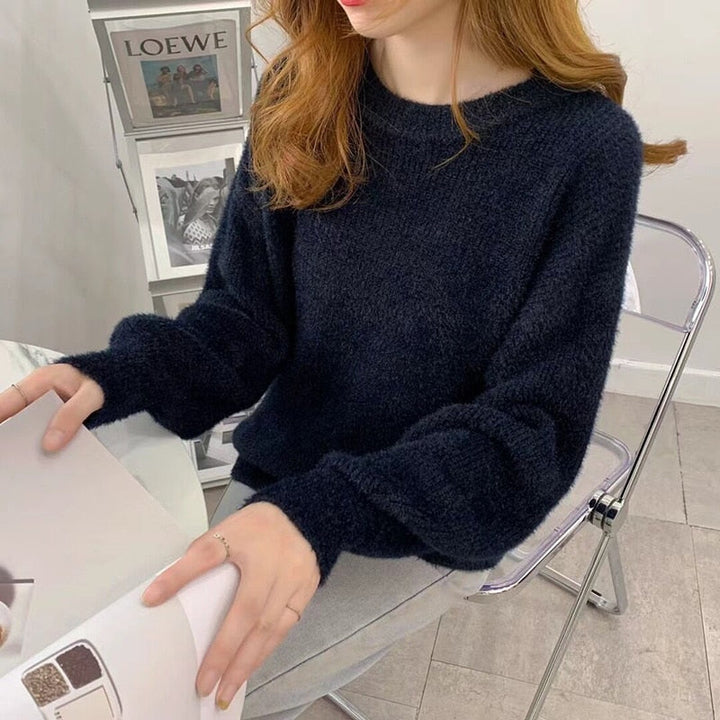 Frau in schwarzem Strickpullover, sitzt an Tisch, modernes Interieur, gemütlicher Look.