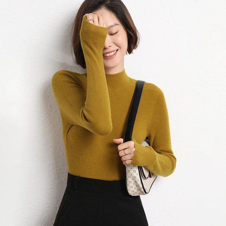 Frau in senfgelbem Strickpullover, lächelnd, mit kleiner Umhängetasche, modisch, elegant.