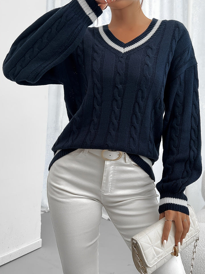 Frau in dunkelblauem Strickpullover und weißen Jeans, hält weiße gesteppte Clutch.