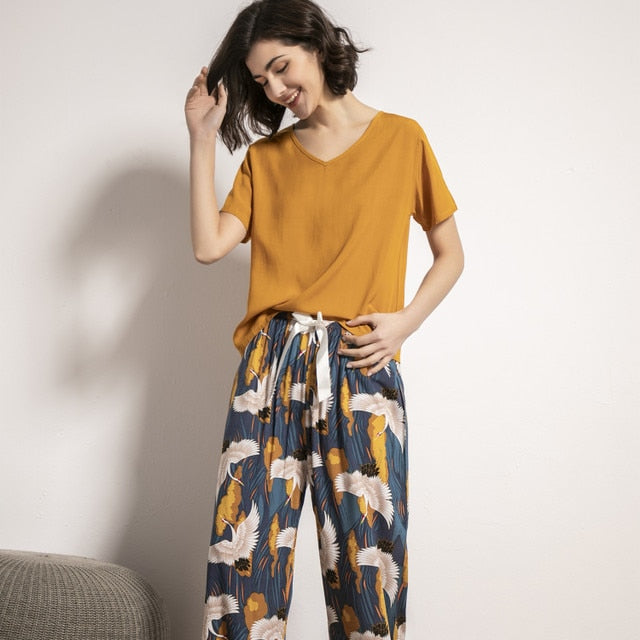 Frau in gelbem T-Shirt und gemusterter Hose, lächelnd, Freizeitmode, bequem, modern.