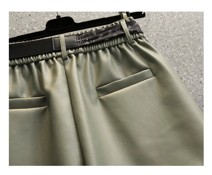 Grüne Lederhose mit elastischem Bund und Taschen, modische Damenbekleidung, Nahaufnahme.