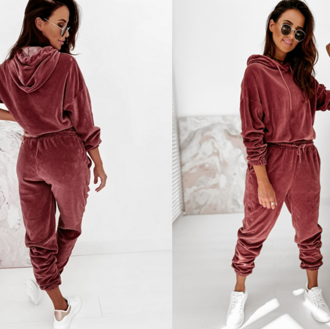 Frau in rosa Samt-Trainingsanzug, Kapuzenpullover, Jogginghose, weiße Sneaker, modisch, bequem.