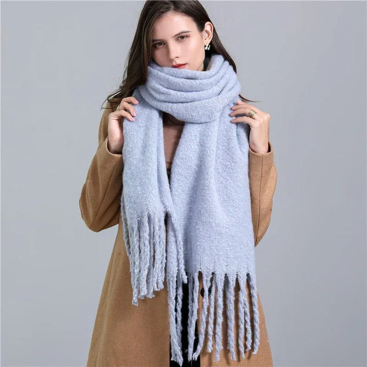 Frau mit hellblauem Strickschal und beigem Mantel, modisches Winteroutfit, Damenaccessoire.