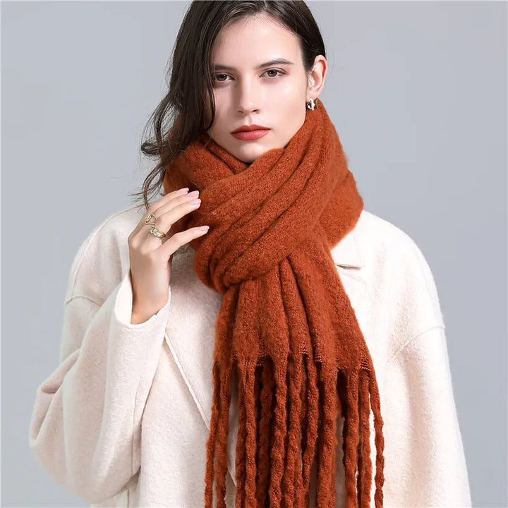 Frau mit braunem Wollschal und weißem Mantel, modisches Winteroutfit, Damenaccessoire.