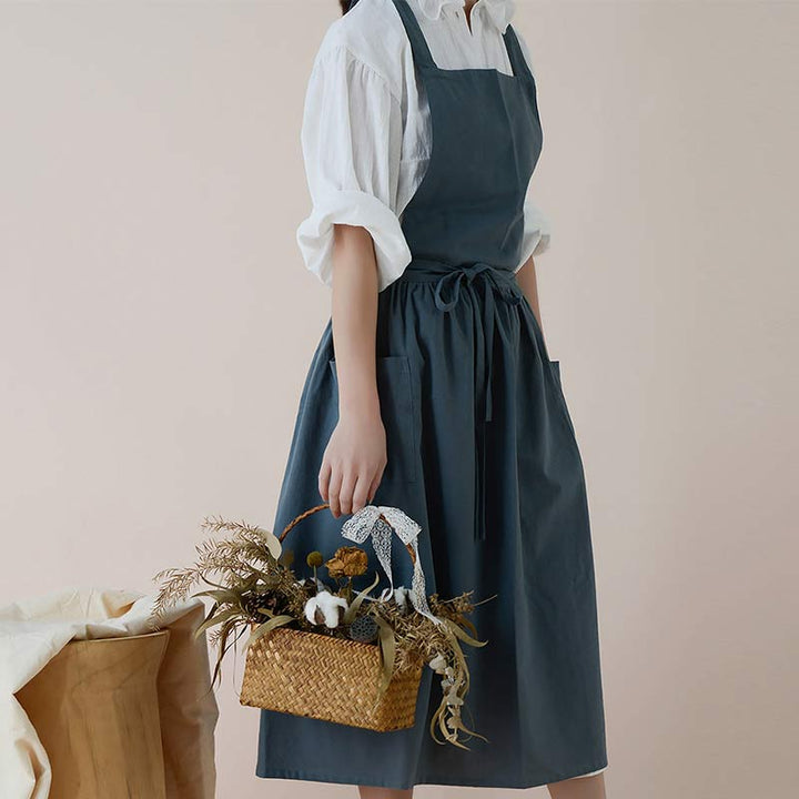 Frau in dunkelblauer Schürze mit Korb, weiße Bluse, Trockenblumen, Küchenschürze, Leinen.