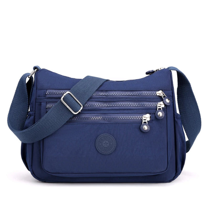 Blaue Umhängetasche mit Reißverschlüssen, verstellbarem Gurt, ideal für Damen, Freizeit, Reisen.