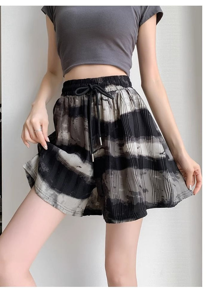 Frau in grauem Crop-Top und schwarz-weiß karierten Shorts, Sommermode, Freizeitkleidung.