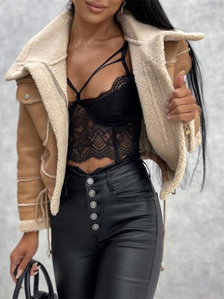 Frau in schwarzem Spitzenoberteil, Lederhose und beiger Jacke mit Schaffellfutter.