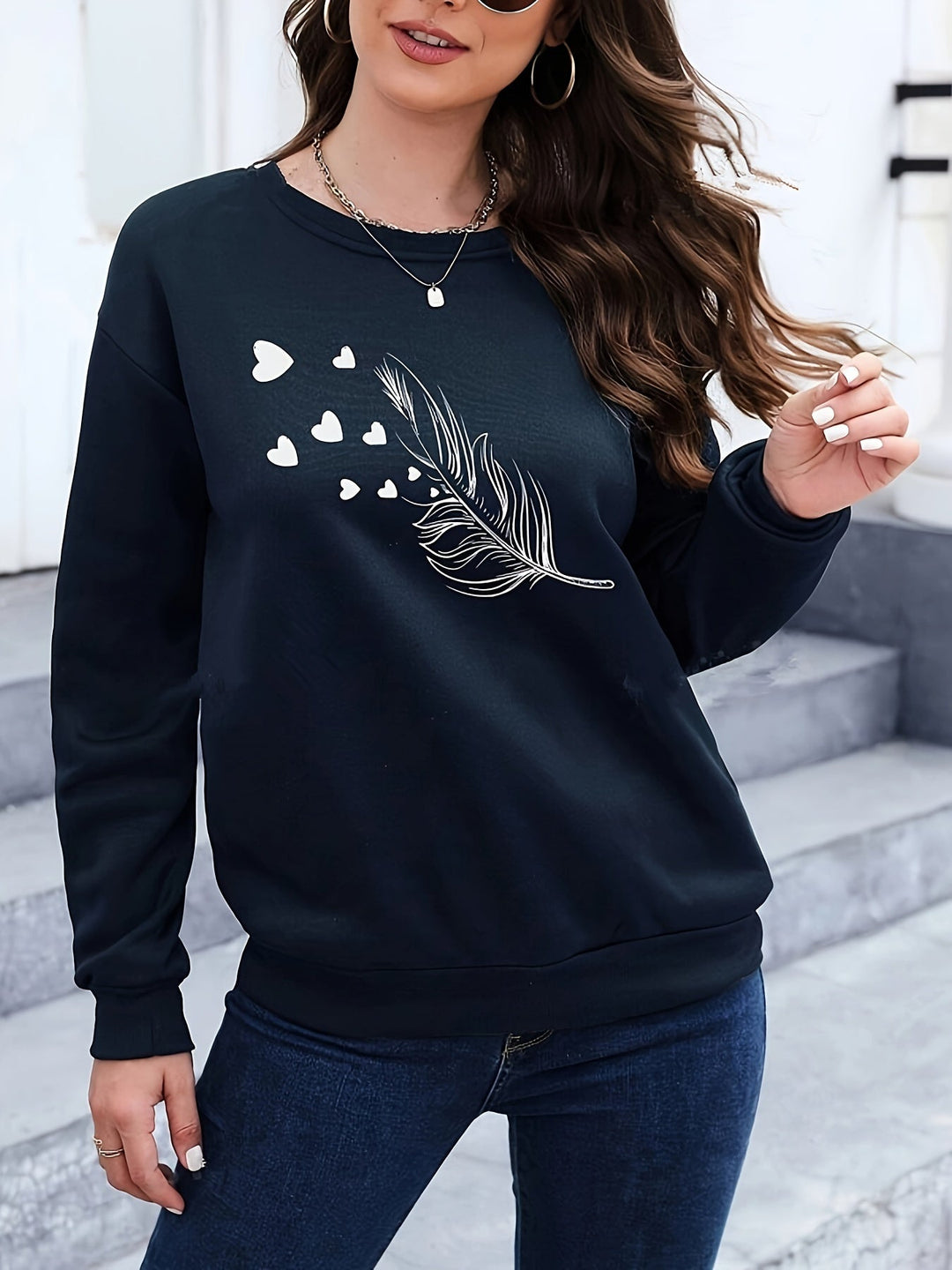 Frau in schwarzem Pullover mit Feder- und Herzmotiv, lässige Mode, Damenbekleidung.