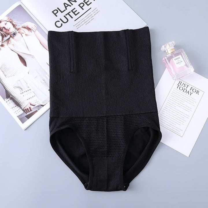 Schwarze Shapewear-Hose, nahtlos, figurformend, auf grauem Hintergrund mit Parfümflasche.
