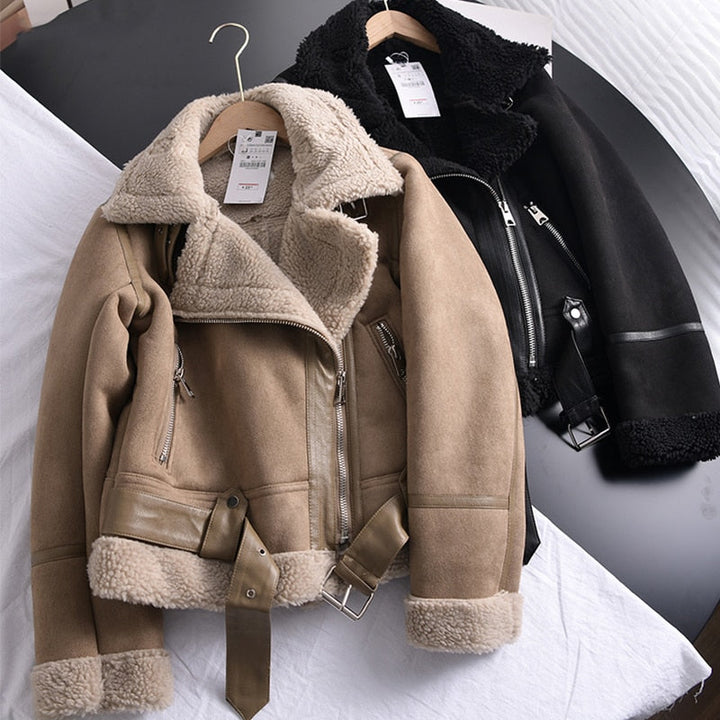 Zwei Fliegerjacken aus Leder, beige und schwarz, mit Reißverschlüssen und Fellfutter auf Kleiderbügeln.