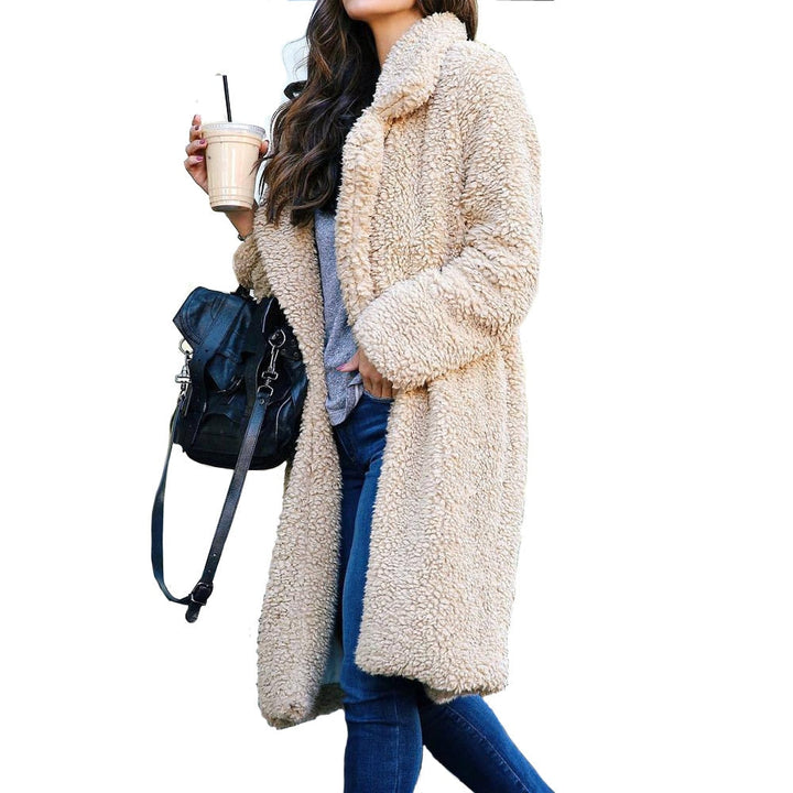 Frau in beigem Teddy-Mantel, hält Kaffee, trägt schwarze Tasche, lässiger Winterlook.