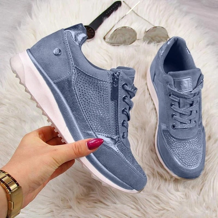 Blaue Damen-Sneaker aus Leder mit Reißverschluss, sportlich, modisch, bequem, auf weißem Teppich.