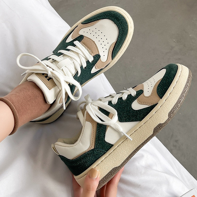 Grüne und weiße Sneaker aus Leder, sportlich, modisch, Damen, auf grauem Hintergrund.