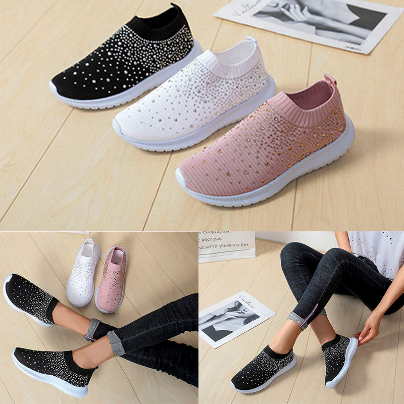 Drei Paar Damen-Sneaker, schwarz, weiß, rosa, mit Strass, auf Holzboden.