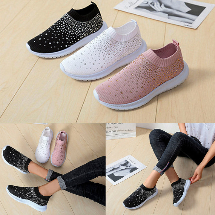Drei Paar Damen-Sneaker, schwarz, weiß, rosa, mit Strass, auf Holzboden.