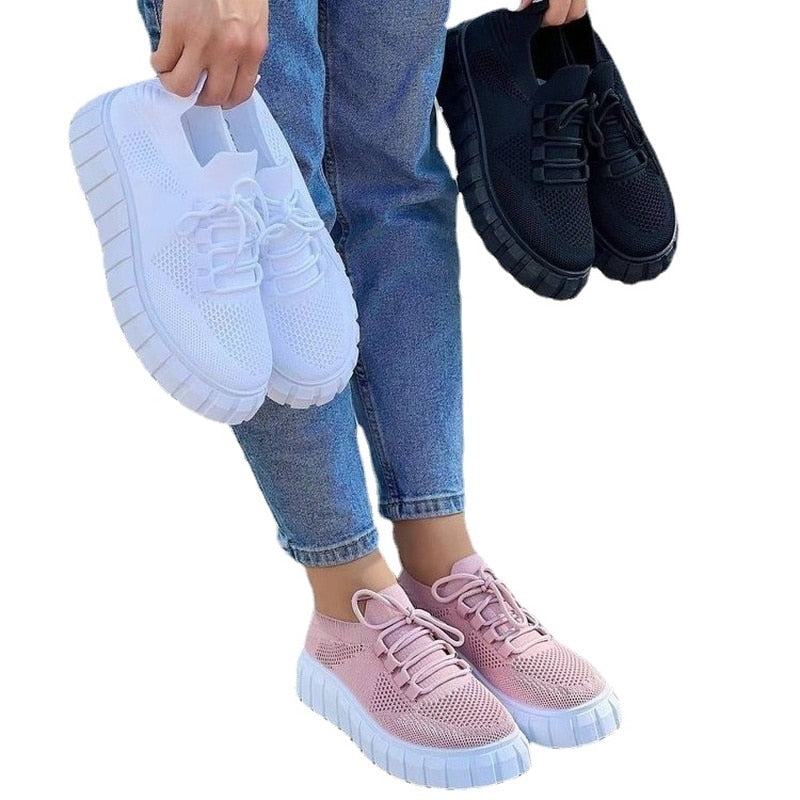 Frau hält drei Paar Sneaker in Weiß, Schwarz und Rosa, atmungsaktiv, modisch, bequem.