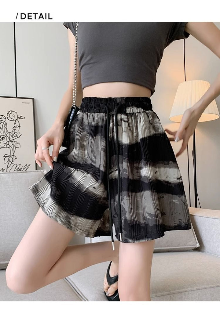 Frau trägt schwarz-weiß gestreifte Shorts, graues Top, modisch, Sommerkleidung, Wohnzimmer.