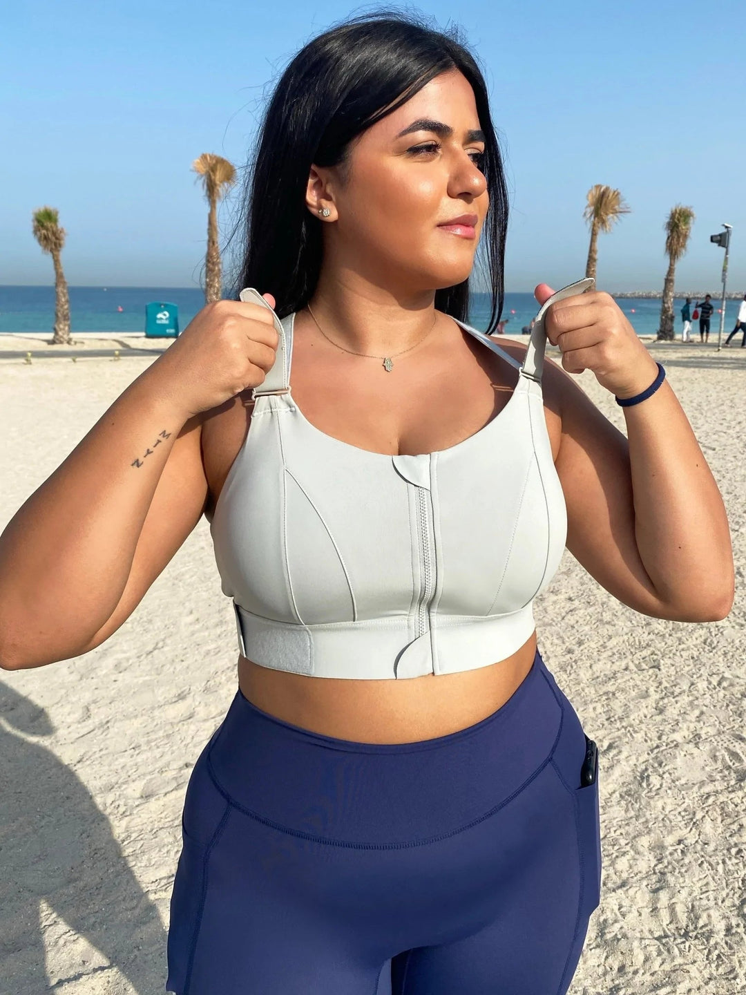 Frau in weißem Sport-BH mit hoher Unterstützung am Strand, Fitnessmode, Sommerkleidung.