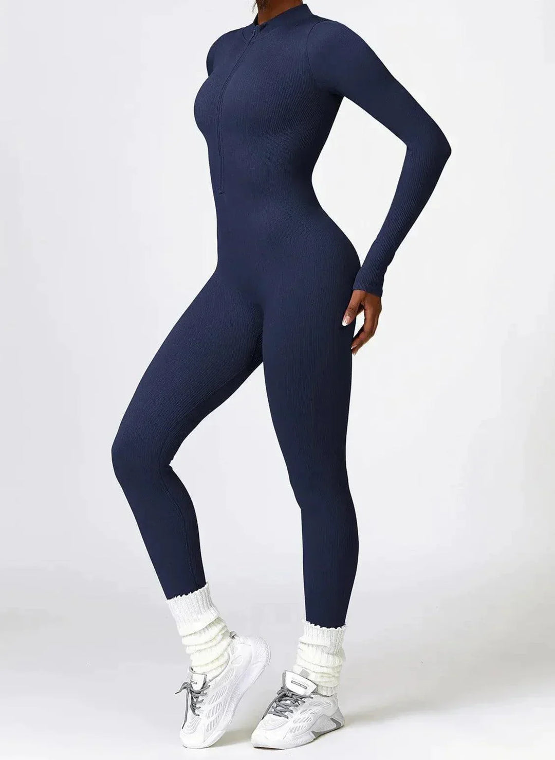 Dunkelblauer Damen-Jumpsuit, langärmelig, figurbetont, für Fitness, mit weißen Sneakers.