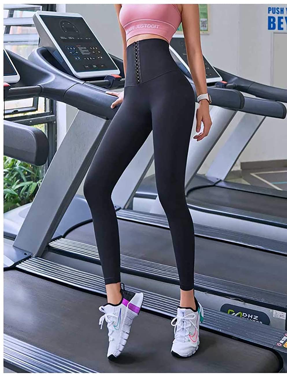 Frau in schwarzer Sportleggings und rosa Top auf Laufband im Fitnessstudio.