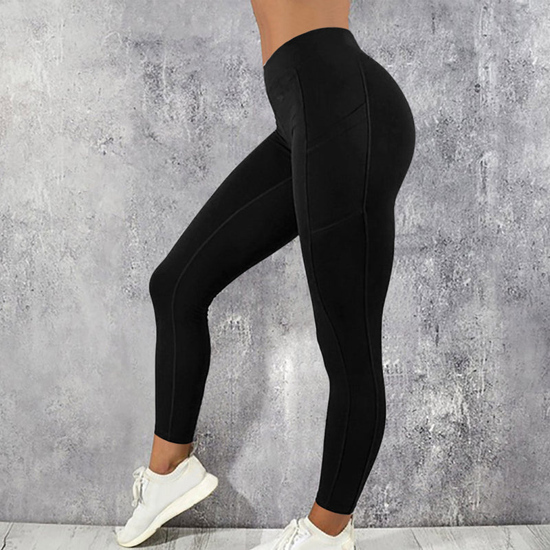 Frau in schwarzer Sportleggings, hohe Taille, vor grauem Hintergrund, weiße Turnschuhe.