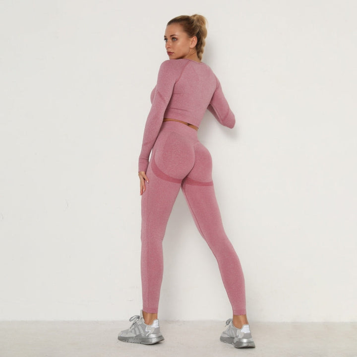Frau in rosa nahtlosem Sportanzug, Langarm, Leggings, Fitnessmode, vor weißem Hintergrund.