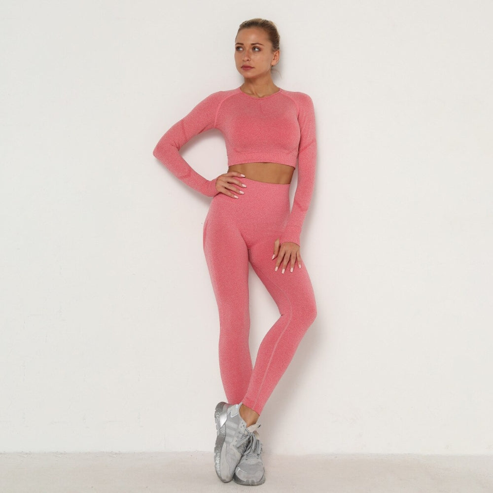 Frau in rosa nahtlosem Sport-Set, Langarm-Top und Leggings, Fitnessmode, vor weißem Hintergrund.