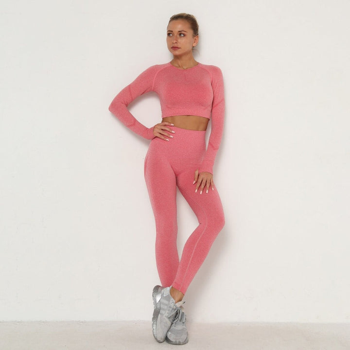 Frau in rosa nahtlosem Sport-Set, Langarm-Top und Leggings, Fitnessmode, vor weißem Hintergrund.