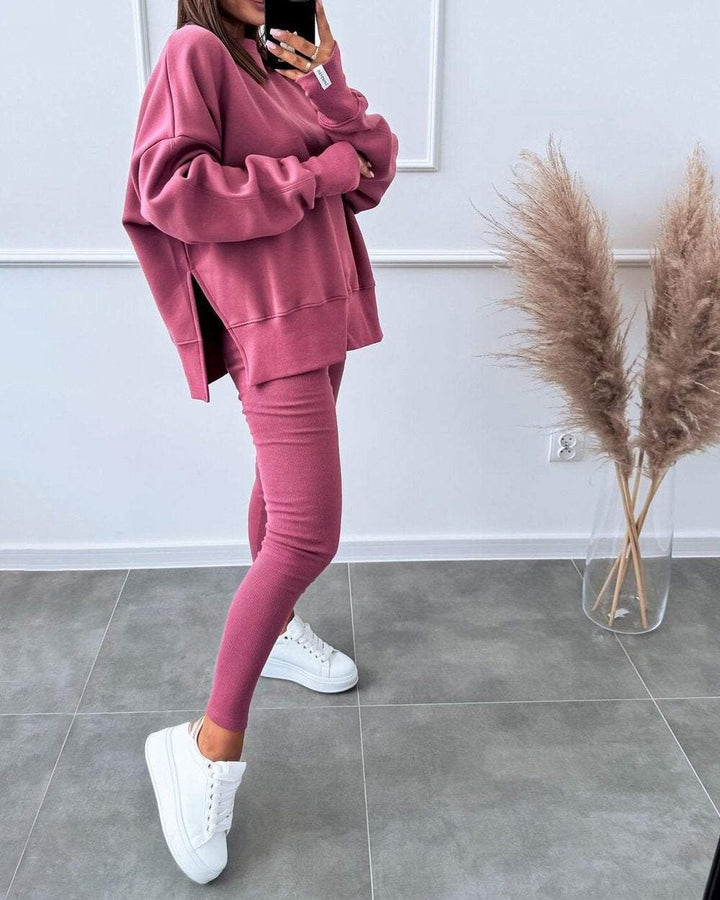 Frau in rosa Oversize-Sweatshirt und Leggings, weiße Sneaker, moderne Freizeitmode.