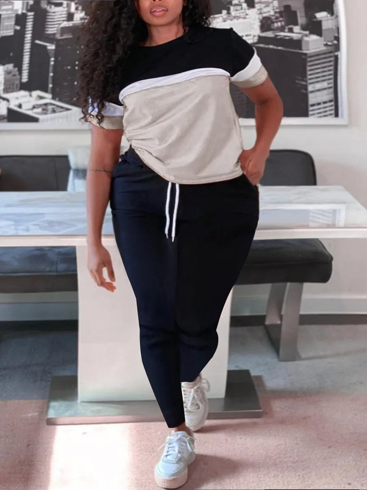 Frau in schwarz-weißem T-Shirt und schwarzer Hose, lässige Mode, urbaner Hintergrund.