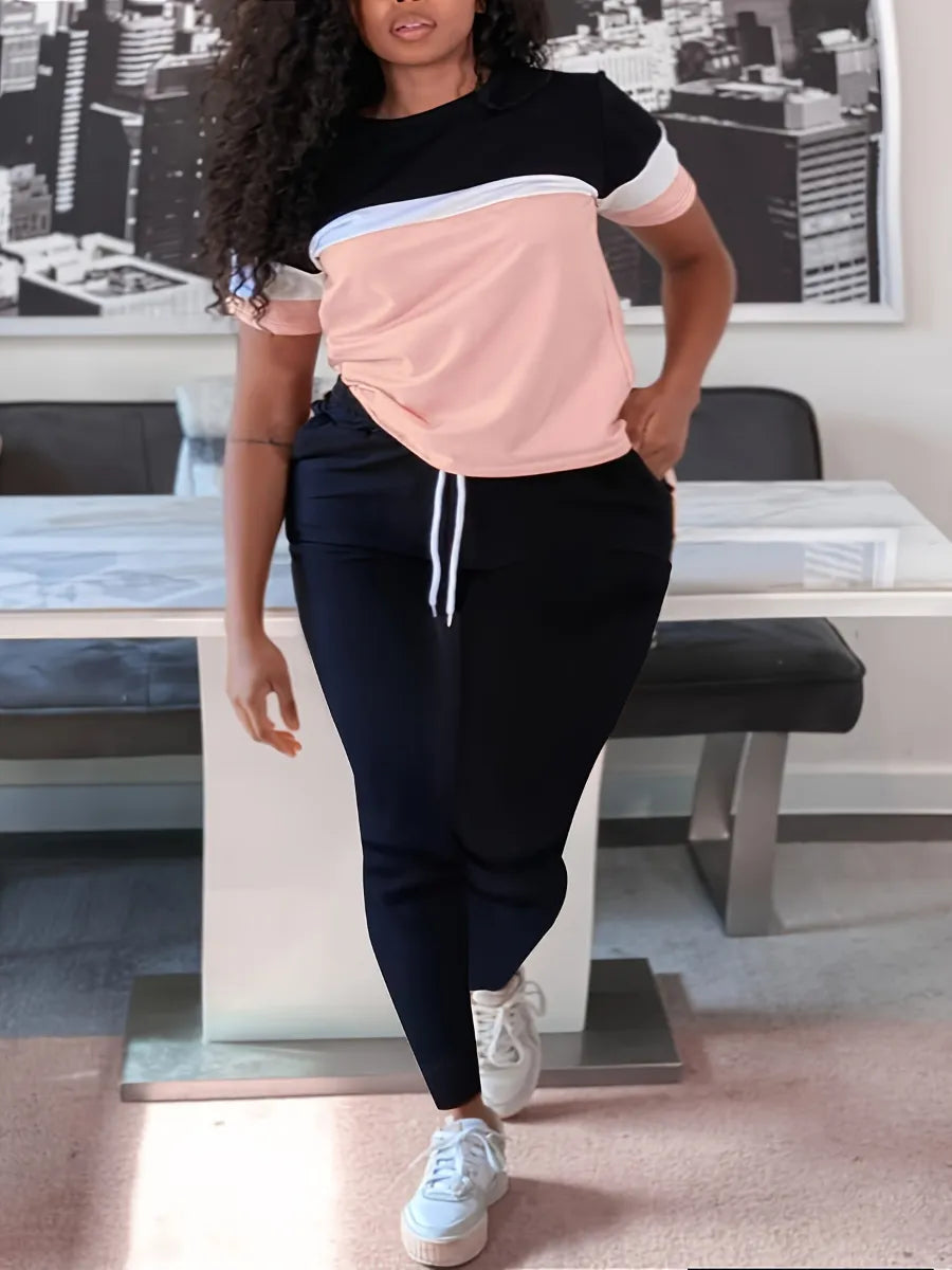 Frau in sportlichem Outfit, schwarz-weißes T-Shirt, schwarze Jogginghose, weiße Sneaker.