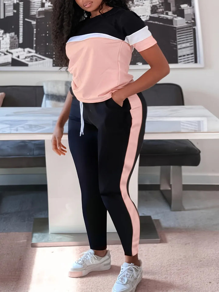 Frau in schwarz-rosa Sportanzug, weißem Streifen, Sneakers, modernes Wohnzimmer.