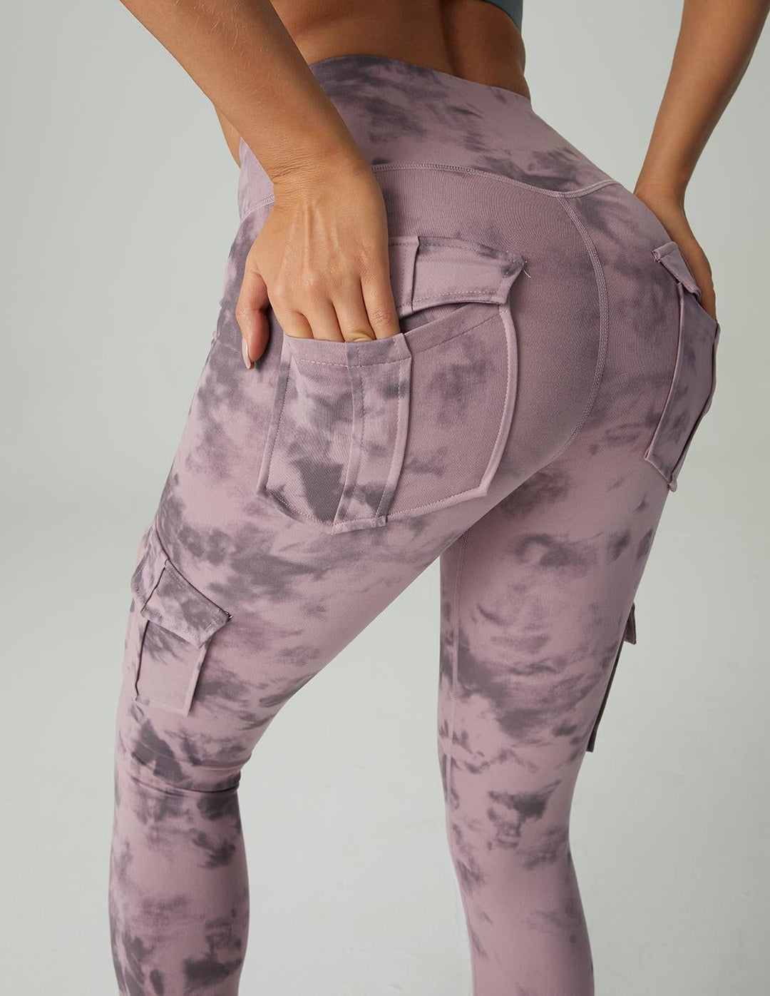 Frau in lila Batik-Leggings mit Taschen, sportlich, modisch, bequem, Freizeitkleidung.