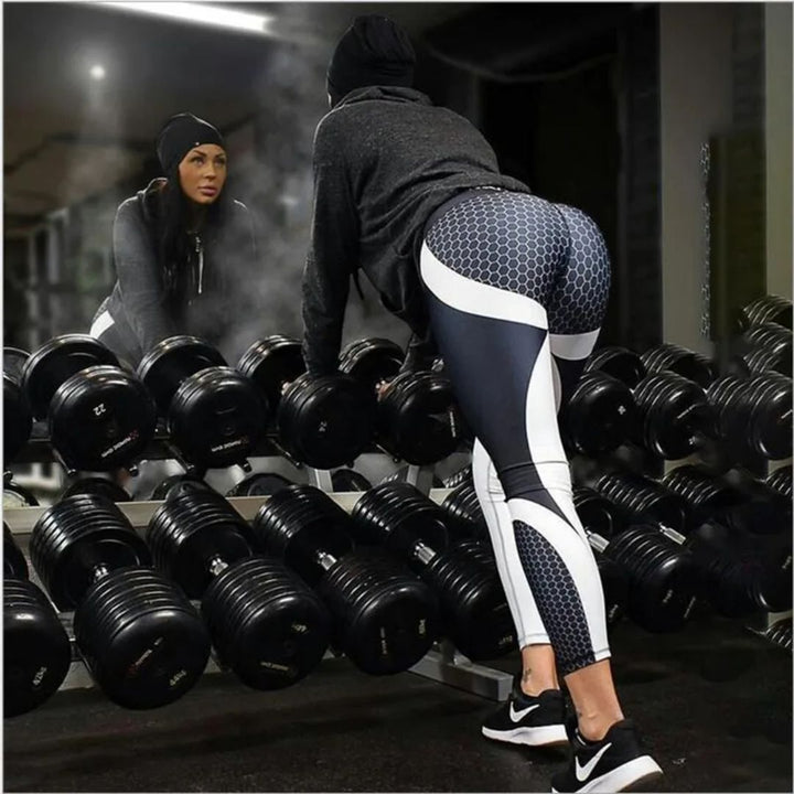 Frau im Fitnessstudio, schwarze Leggings, Hanteln, Spiegel, Sportbekleidung, Training, Gym.