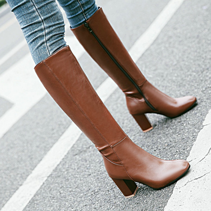 Braune Damenstiefel mit Absatz, Reißverschluss, aus Leder, elegant, auf Gehweg.