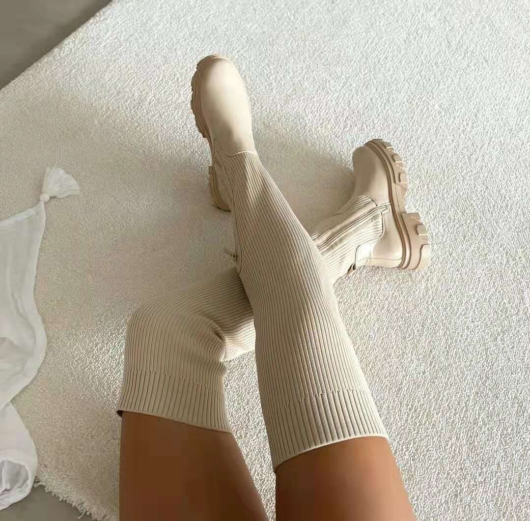Beige kniehohe Stiefel mit dicker Sohle auf Teppich, modisch, Damenmode, Herbsttrends.
