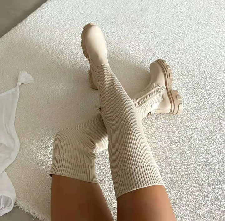 Beige kniehohe Stiefel mit dicker Sohle auf Teppich, modisch, Damenmode, Herbsttrends.