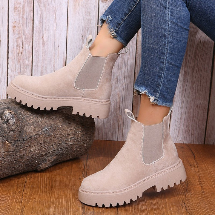 Beige Chelsea Boots aus Wildleder mit dicker Sohle, Damenmode, lässiger Stil, Holzhintergrund.