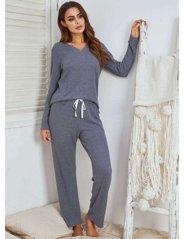 Frau in grauem Strick-Pyjama-Set, gemütliche Damenmode, V-Ausschnitt, Freizeitkleidung.