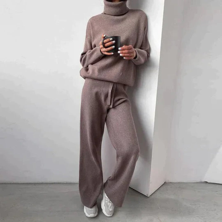 Frau in braunem Strickpullover und Hose, hält Tasse, lässige Mode, gemütlicher Look.