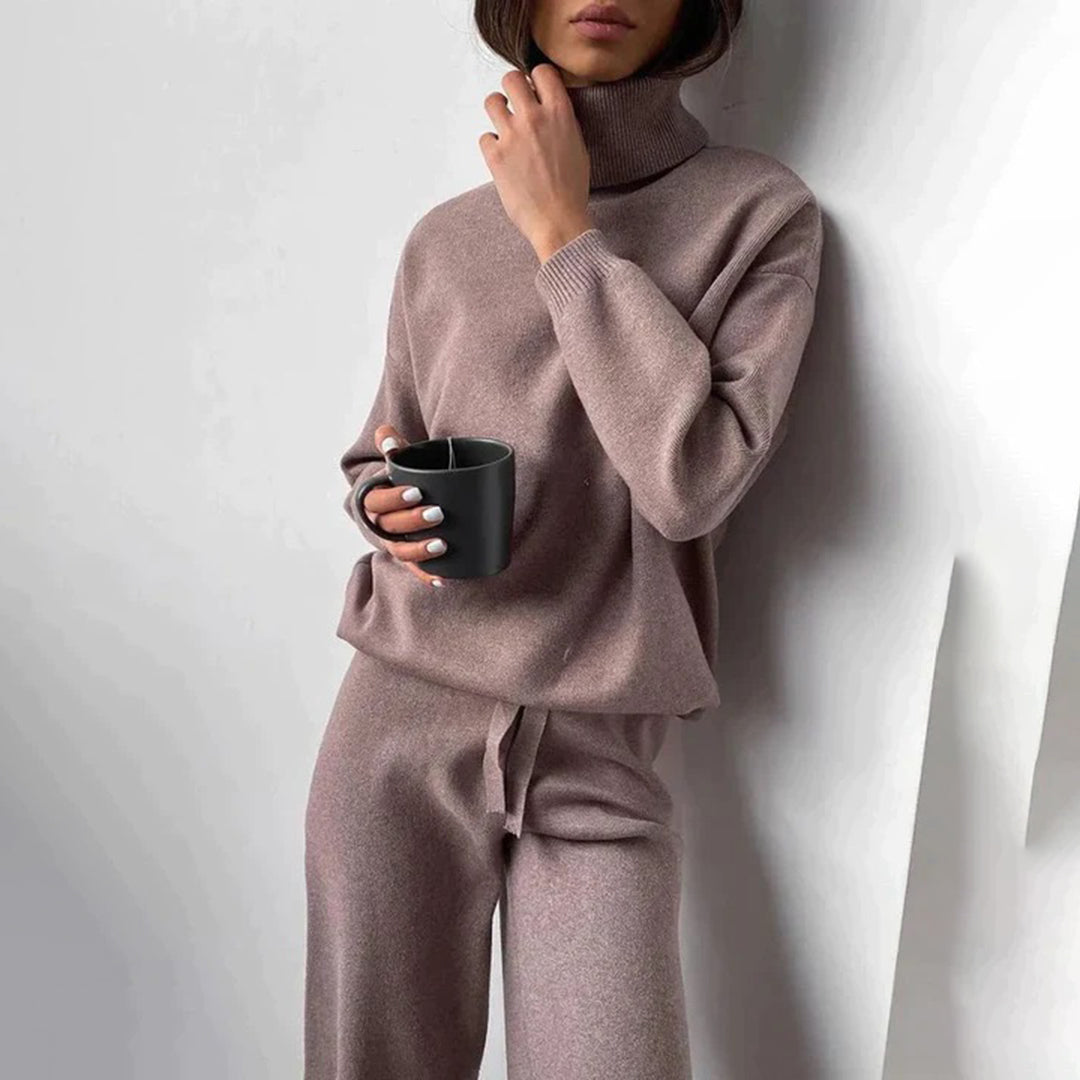 Frau in braunem Strickpullover und Hose hält schwarze Tasse, gemütliche Mode, Herbstoutfit.