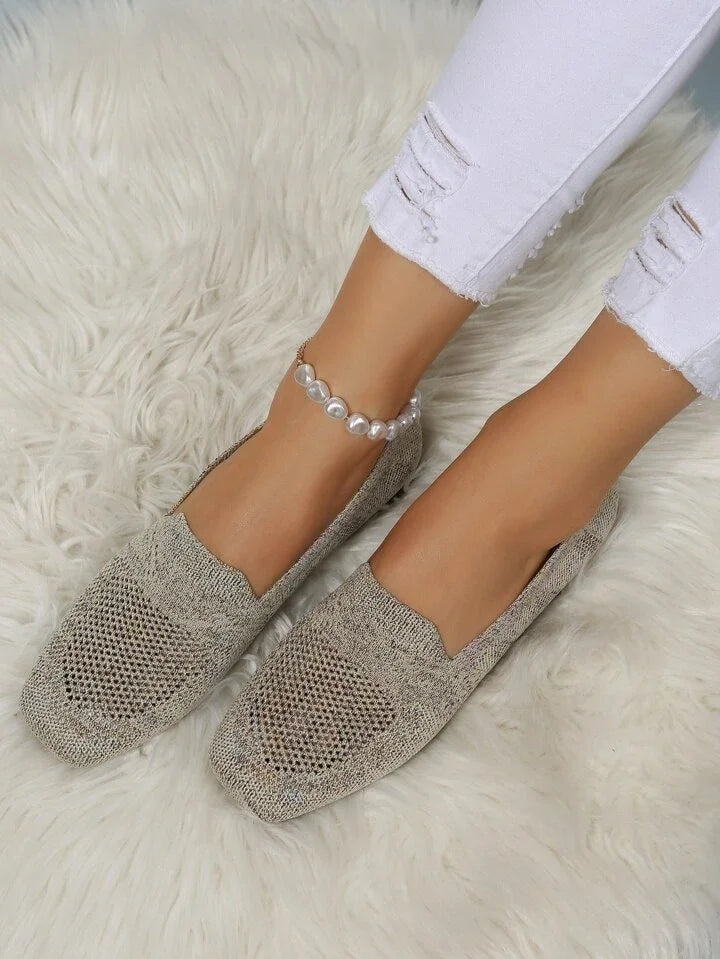 Damen Strick-Slipper beige, bequem, atmungsaktiv, auf weißem Teppich, modisch, lässig.