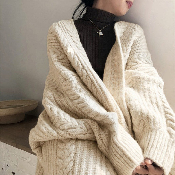 Frau trägt cremefarbenen Strickpullover, Zopfmuster, gemütlich, modisch, Herbst-Winter-Look.