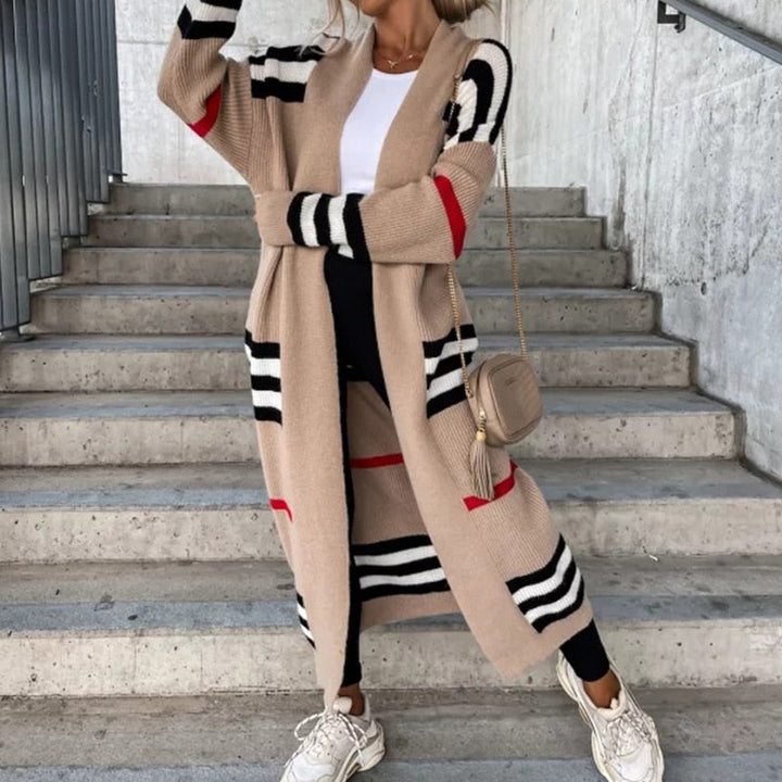 Frau in langem, gestreiftem Cardigan, beige mit schwarzen und roten Streifen, auf Treppe.