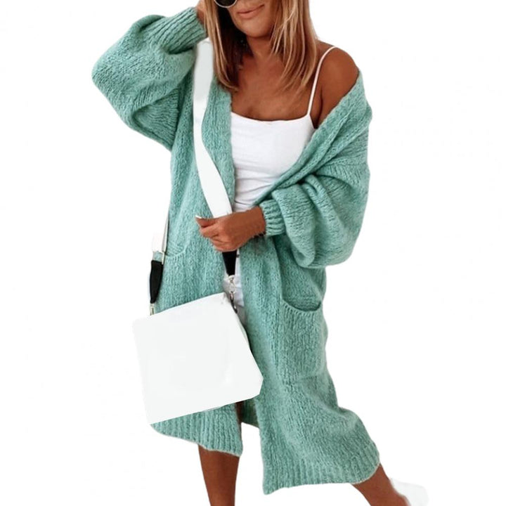 Frau in mintgrünem Strickcardigan, weißes Top, weiße Umhängetasche, lässige Mode.