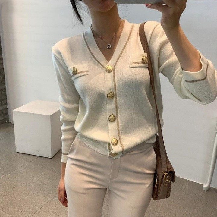 Frau in cremefarbenem Cardigan mit goldenen Knöpfen, elegantes Outfit, modisch, stilvoll.