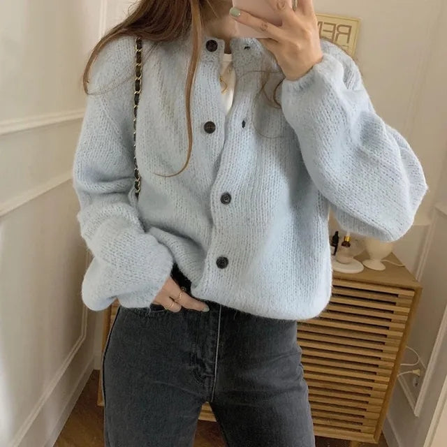 Frau trägt hellblauen Oversize-Strickcardigan mit Knöpfen, kombiniert mit schwarzer Jeans.